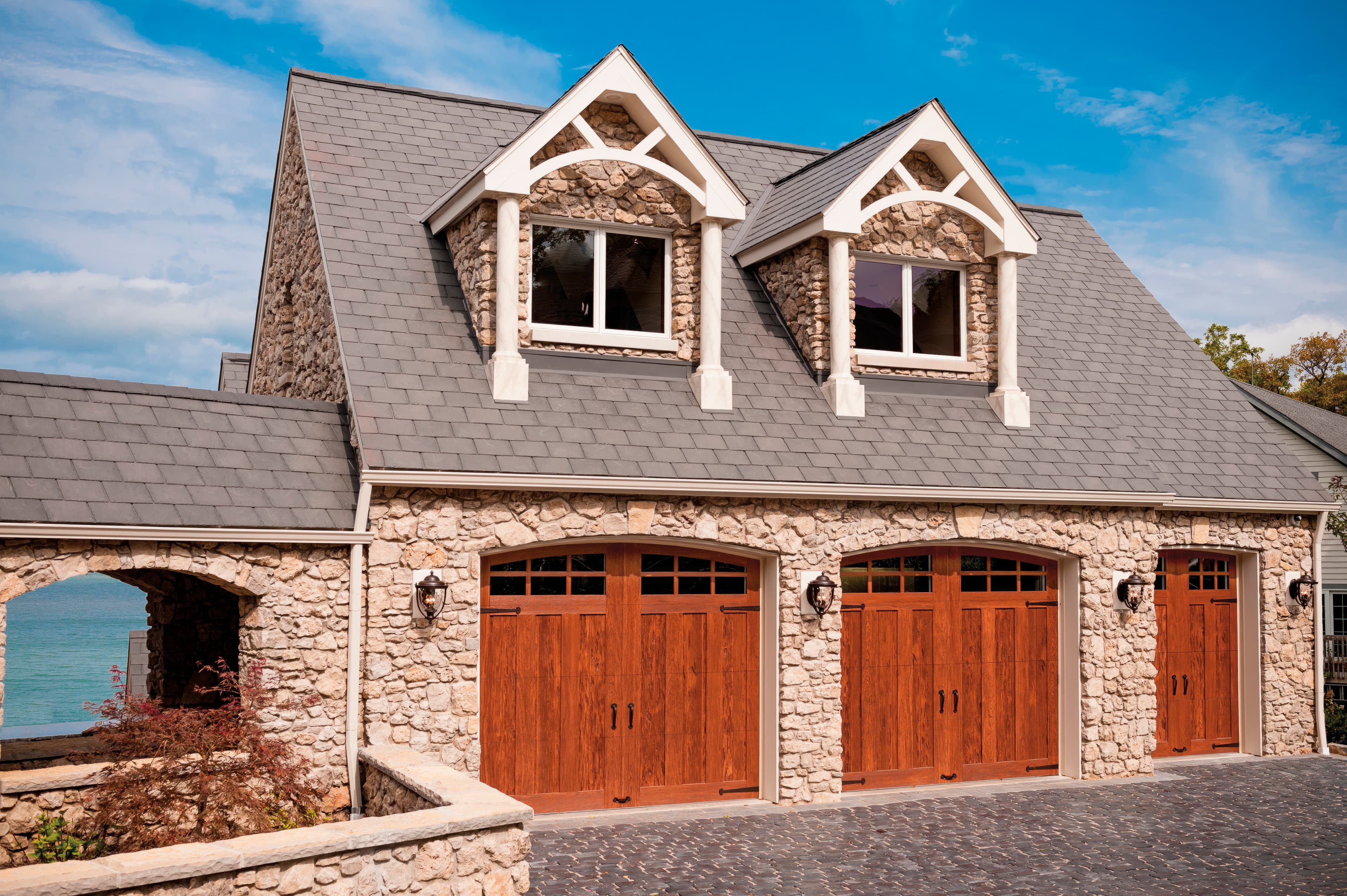Stone estate home with rich wood Canyon Ridge carriage house garage doors and arched windows