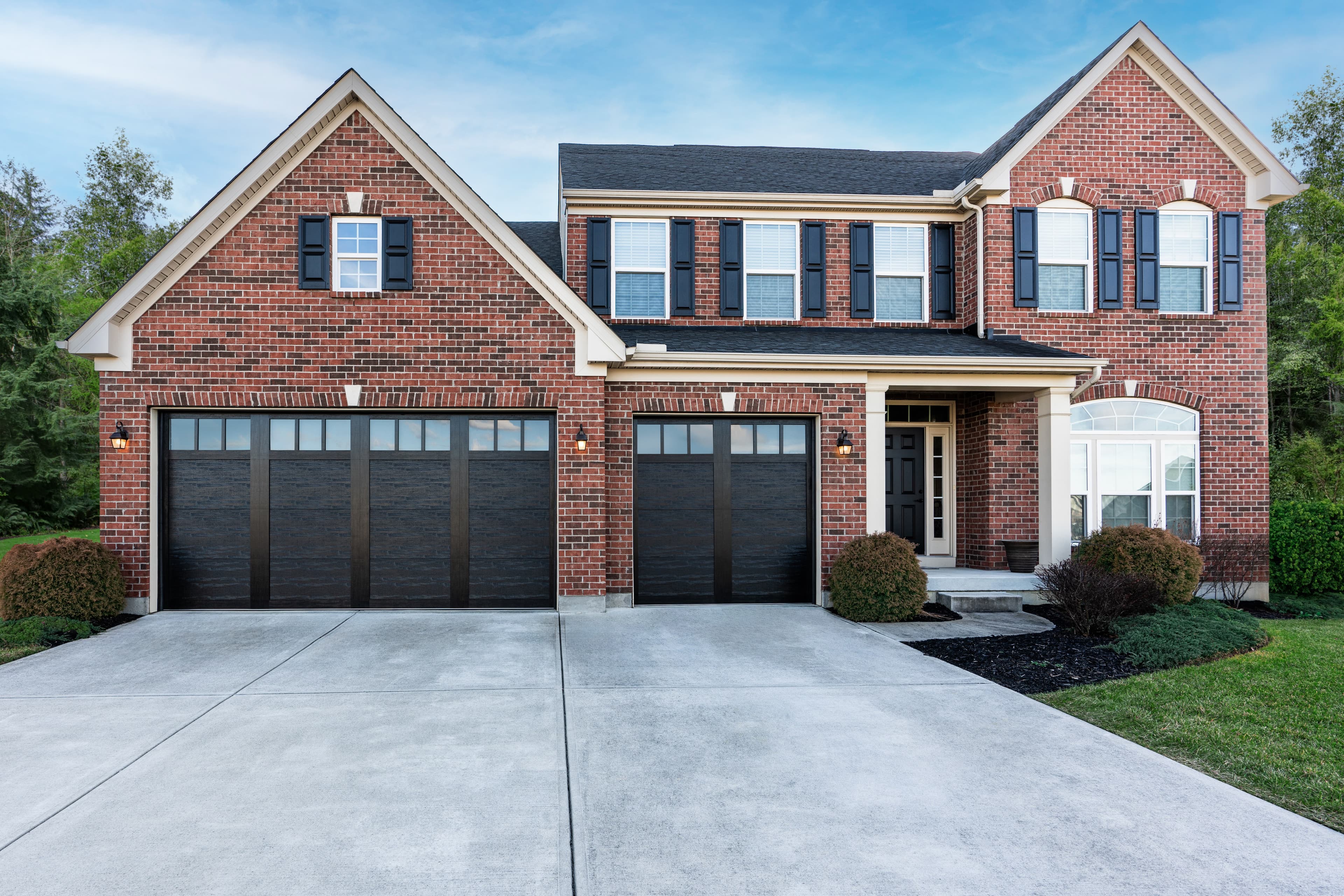 Brick colonial home with modern dark flush garage doors and manicured landscaping