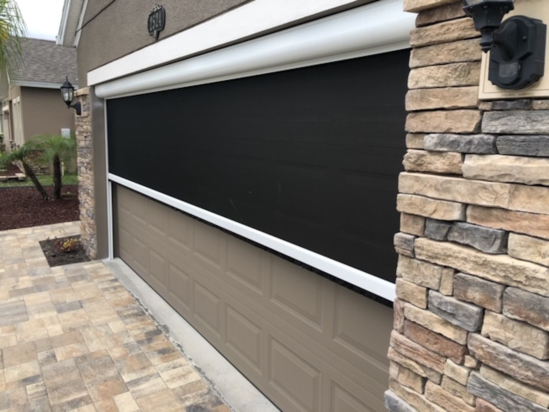 Motorized retractable garage screen door installation on residential home
