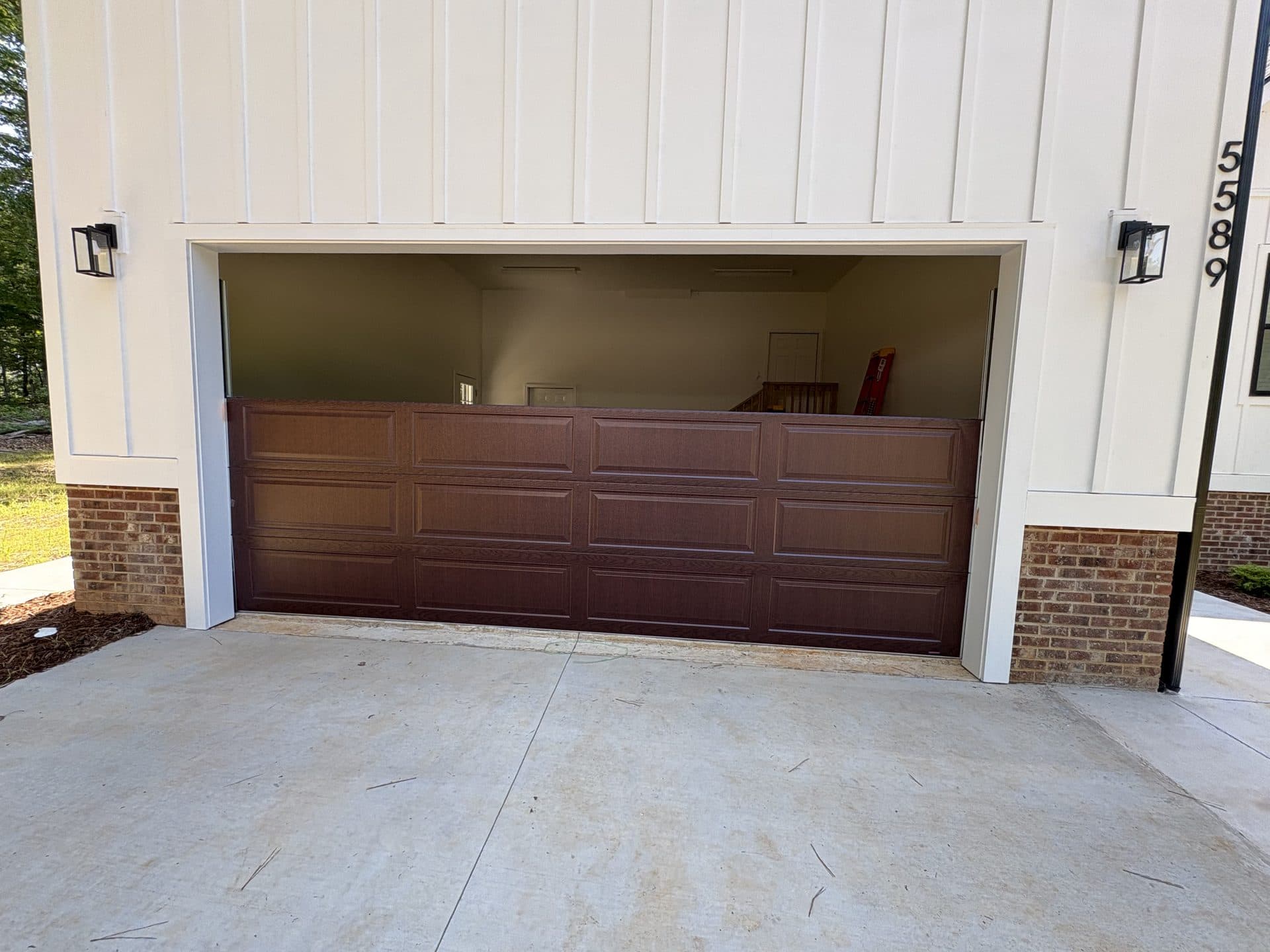 Dark walnut woodgrain garage door on modern farmhouse with board-and-batten siding in Mooresville NC