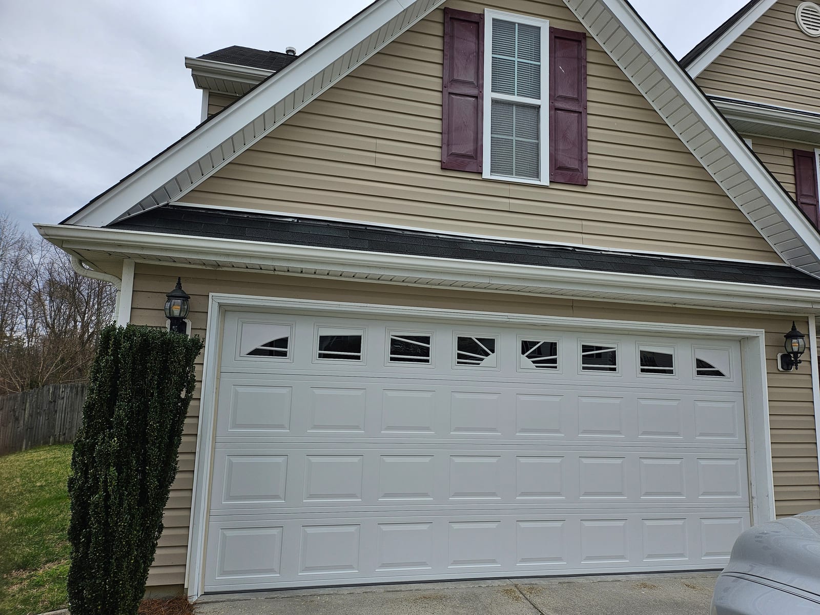 New white raised-panel garage door with sunburst windows completed exterior view