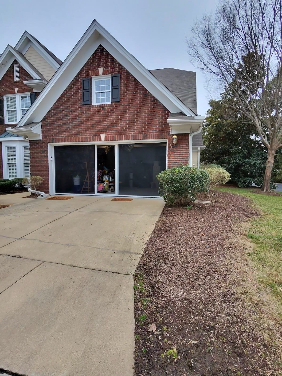 Two-bay retractable screen door system on upscale brick home exterior