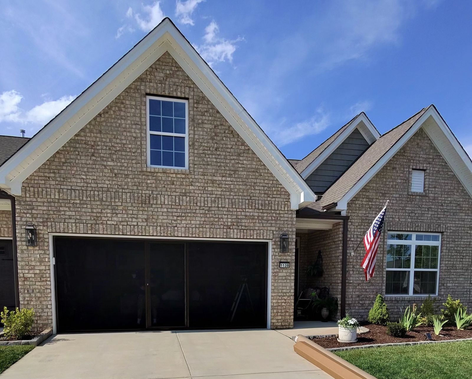 Premium garage screen door on brick home with American flag in Advance NC